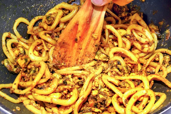 Cozinhar mexilhão e lula em uma frigideira. misturando frutos do mar por uma colher de madeira . — Fotografia de Stock