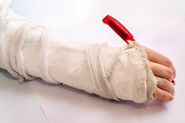 Scrittura a mano con la penna rossa con bendaggio medicinale sul gomito lesione — Foto Stock