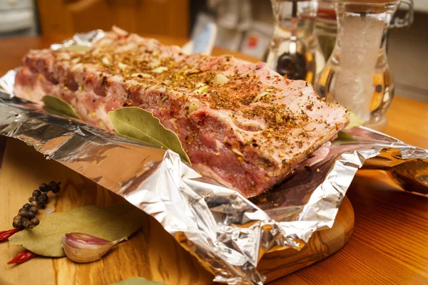 Costelas de porco frescas, carne marinada e preparada para assar com alho em papel alumínio — Fotografia de Stock