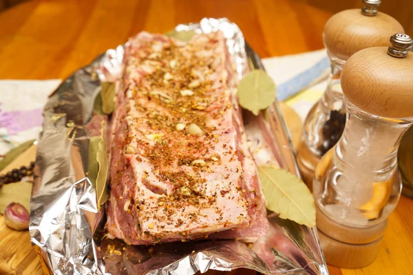 Costelas de porco frescas, carne marinada e preparada para assar com alho em papel alumínio — Fotografia de Stock