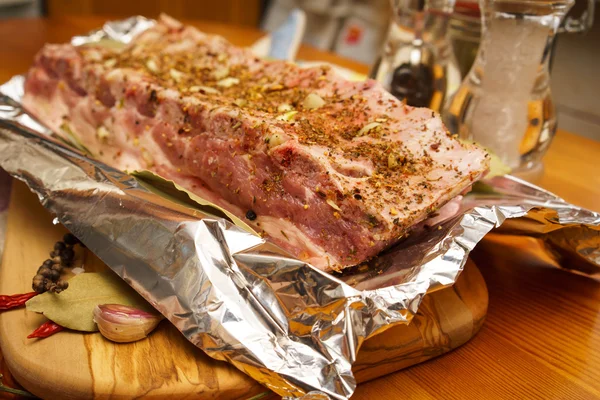 Costelas de porco frescas, carne marinada e preparada para assar com alho em papel alumínio — Fotografia de Stock