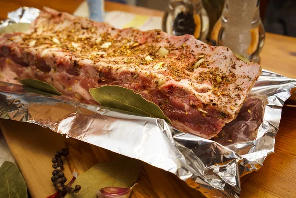 Costillas de cerdo frescas, carne marinado y preparado para asar con ajo en una lámina —  Fotos de Stock