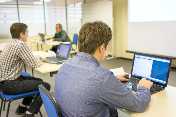 Folk sitter på kontoren och skriva på tangentbord för sina bärbara datorer i en klass och tränare på backstage — Stockfoto