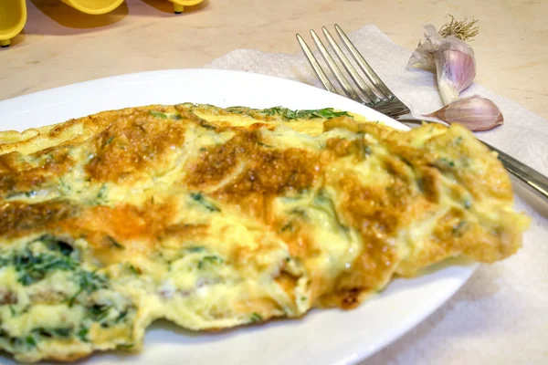 Savoury omelette with dill on the plate, fork and garlik on the side — Stock Photo, Image