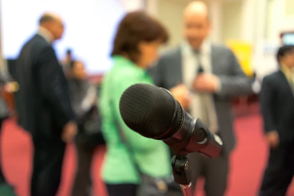 Microphone in focus against blurred audience — Stock Photo, Image