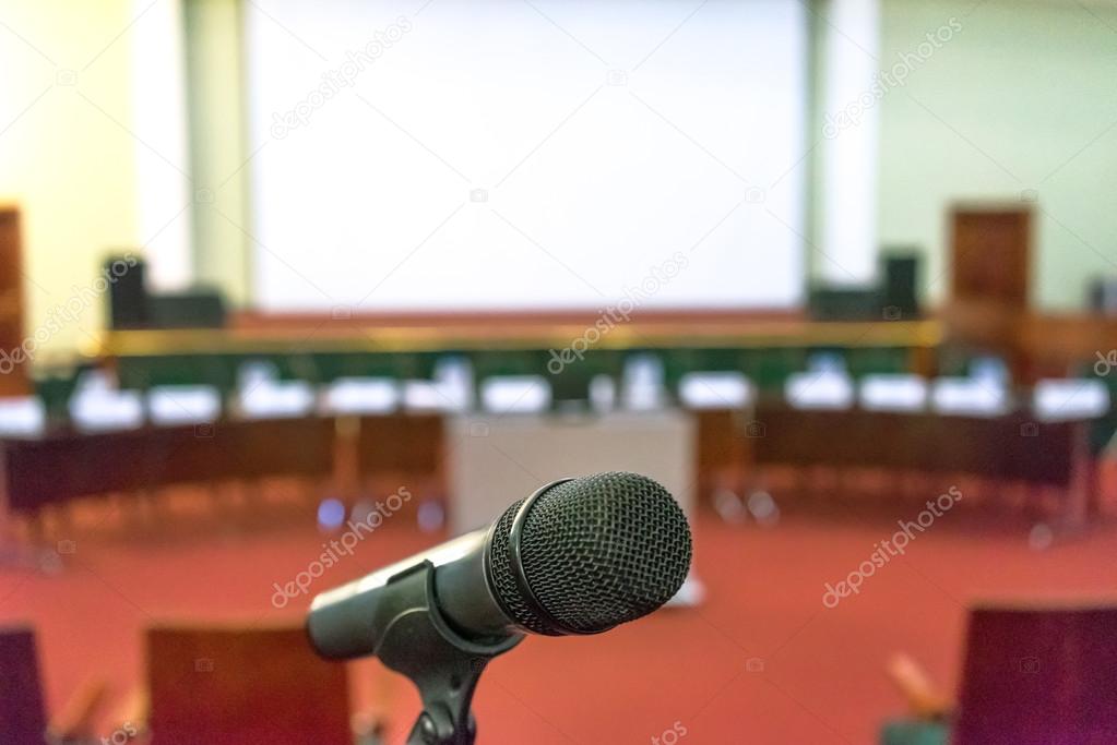 Microphone in focus against blurred podium and screen