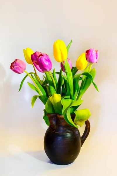 Kytice z fialové a žluté tulipány v starý hliněný hrnec — Stock fotografie