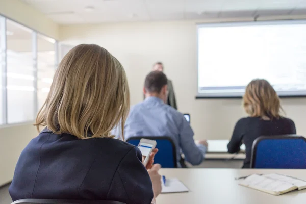Personer som sitter bak på kontoren i klassen utbildning och föreläsaren nära vita skrivbordet — Stockfoto