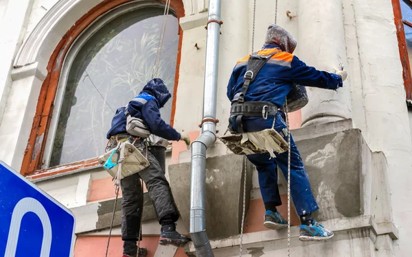 Un maçon qui travaille sur le haut bâtiment. Entretien des bâtiments : deux hommes travaillant en hauteur . — Photo