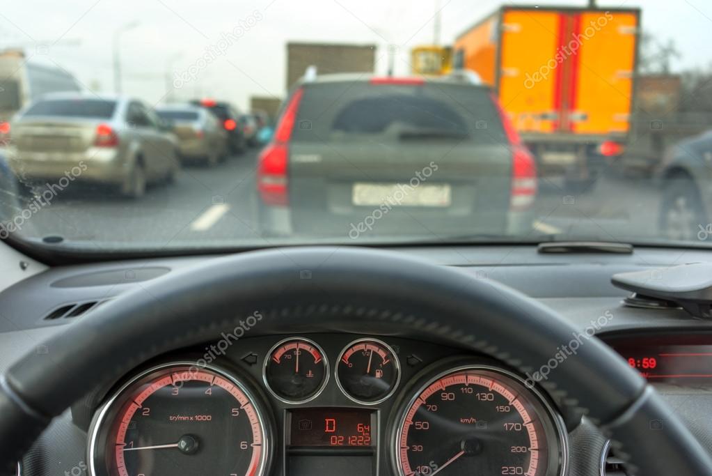 Inside a car steering wheel of a car and motion blurred asphalt road
