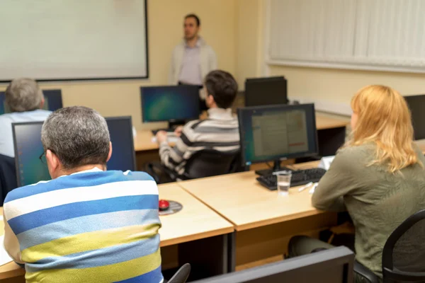 Lärare undervisning klass och två män sitter i öronhöjd och skrivbord — Stockfoto