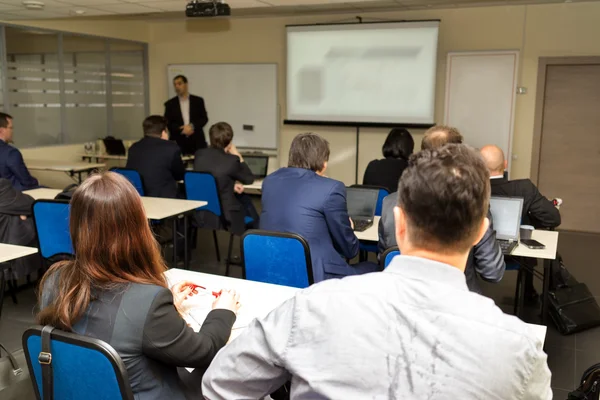 Lärare undervisning klass och två män sitter i öronhöjd och skrivbord — Stockfoto