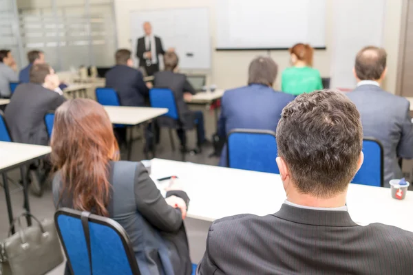 Vue arrière des gens d'affaires qui écoutent attentivement assis dans la salle de classe — Photo