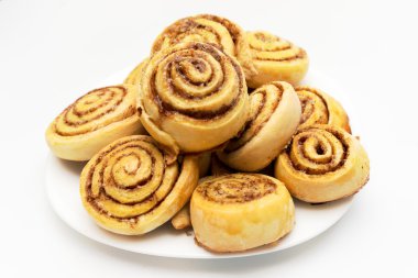 Beyaz arka plan üzerinde izole bir tabak taze tatlı ev yapımı tarçın rulo
