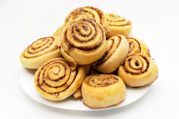 Beyaz arka plan üzerinde izole bir tabak taze tatlı ev yapımı tarçın rulo