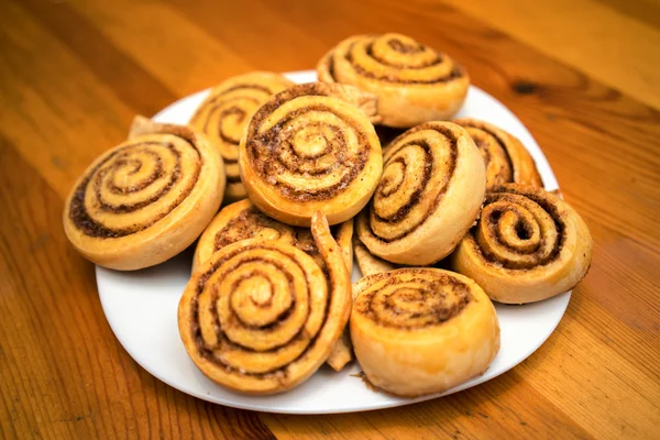 Cinnamon rolls on a white dish in a wooden table — Stock Photo, Image