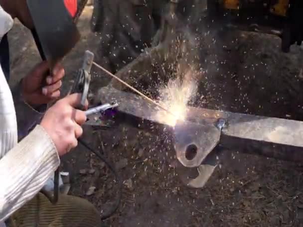 Worker with protective mask welding metal part of the tractor — Stock Video