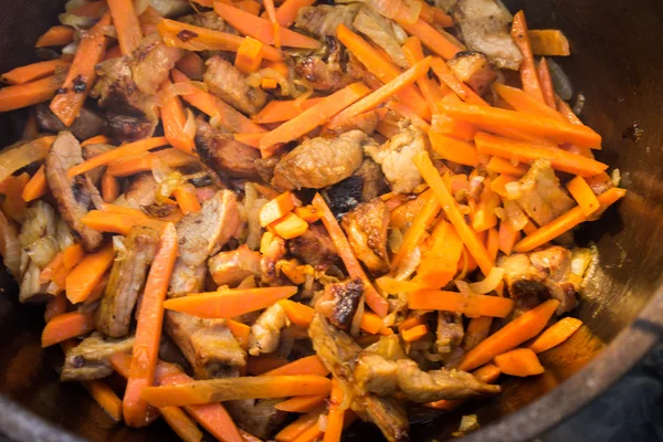 Close up view of cooking meat, onion and carrot in a metal pan in a campfire — Stock Photo, Image