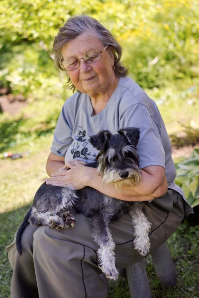 Senior woman hugs her black and silver miniature schnauzer dog in countryside — 图库照片
