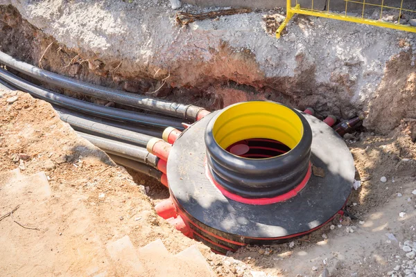 Fosa de excavación, cables eléctricos y fibras ópticas en la excavación en una obra de construcción — Foto de Stock