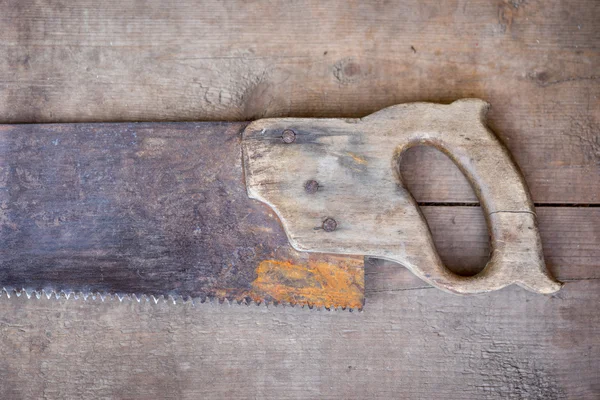 Old saw  with the wooden handle is leaning against the old wooden floor. Copy space — Stock Photo, Image