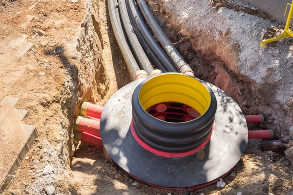 Excavation pit, electrical cables and optical fibres in the digging on a construction site — Stock Image Excavation pit, electrical cables and optical fibres in the digging on a construction site Royalty Free Stock Photos