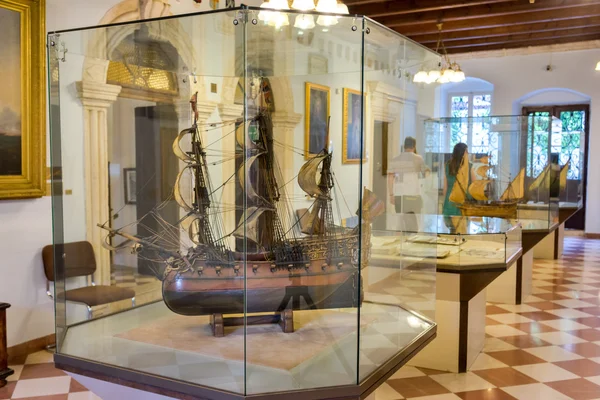 KOTOR, MONTENEGRO - SEPTEMBER 10, 2015: Maritime Museum of Montenegro. Visitors looking at the exponates in the museum hall. Vessel model on the first stage, — Stockfoto