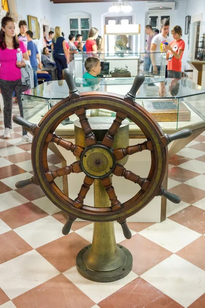 KOTOR, MONTENEGRO - SEPTEMBER 10, 2015: Maritime Museum of Montenegro. Steering wheel of the ship and people in blur at the back stage in the museum hall. — Stock Photo, Image