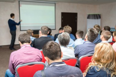 Konferans İzleyici: iş eğitim ve öğretim görevlisi işaret vasıl belgili tanımlık perde beyaz tahta yakınındaki arkada oturan insanlar