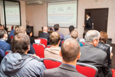 öğretmen beyaz projektör slayt ekranı ile sınıfın önünde ile bir konferans odasında oturan öğrenciler