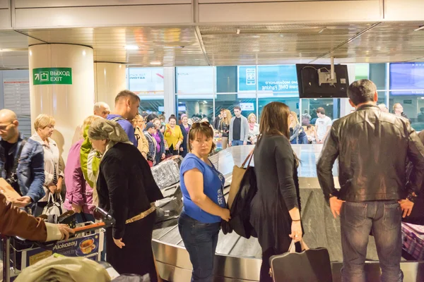 Moscú, Rusia - 16 de septiembre de 2015: multitud de pasajeros esperando recoger su equipaje en el transportador de equipaje en la sala de llegadas del edificio de la terminal del aeropuerto — Foto de Stock