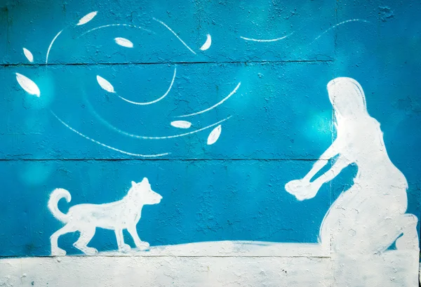 Moscou, Rússia - 27 de setembro de 2015: uma silhueta azul e branca de uma pessoa pintada na parede da garagem. Mulher sentada de joelhos e brincando com um cachorro . — Fotografia de Stock