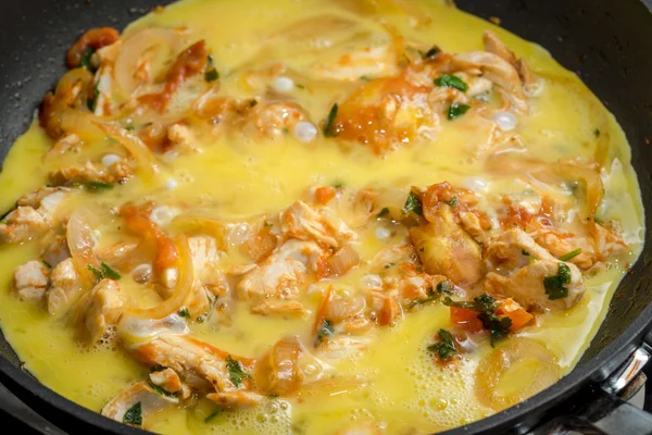 Perto de omelete de cozinha com cebola, tomates, frango e salsa em uma panela de ato de fritar — Fotografia de Stock