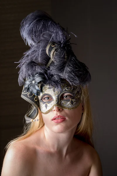 Retrato de una hermosa mujer caucásica joven en una máscara veneciana negra sobre un fondo gris oscuro — Foto de Stock