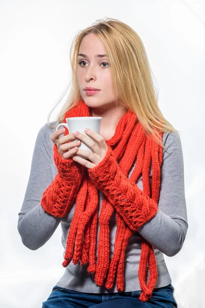 Retrato de uma jovem mulher em cachecol vermelho e mitenes segurando xícara com café ou chá isolado em um fundo branco — Fotografia de Stock