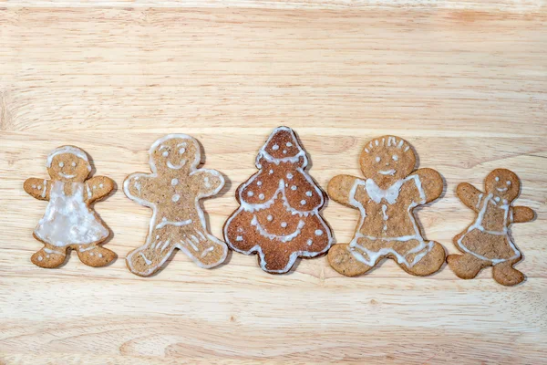 Gingerbread homemade figures of four people together with christmas tree in the middle of a group on a wooden board with copy space for your text — Stock fotografie