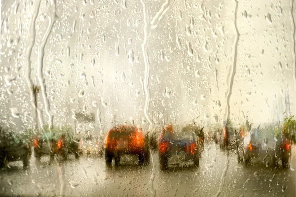 Street in the rain through the window of the car, on a cold, wet day, shot through a windscreen, focusing on the rain droplets. with copy space for your text on the sky. — 图库照片