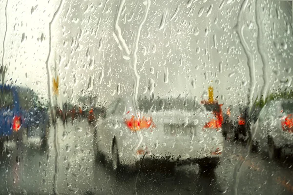 Deszcz na ulicy przez szyby samochodu miasta — Zdjęcie stockowe
