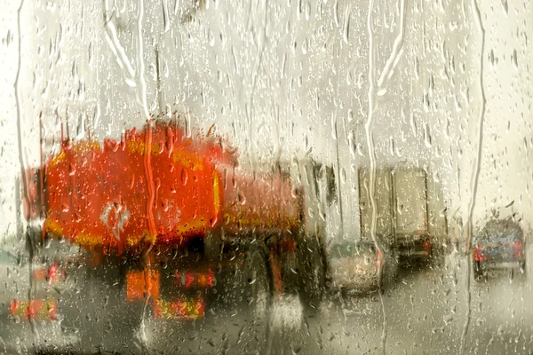 Δείτε μέσα από το παρμπρίζ αυτοκινήτων στο δρόμο με κινούμενα αυτοκίνητα σε μια βροχερή μέρα του φθινοπώρου, εστιάζοντας τα σταγονίδια βροχής. με αντίγραφο χώρο για το κείμενο σας στον ουρανό. — Φωτογραφία Αρχείου