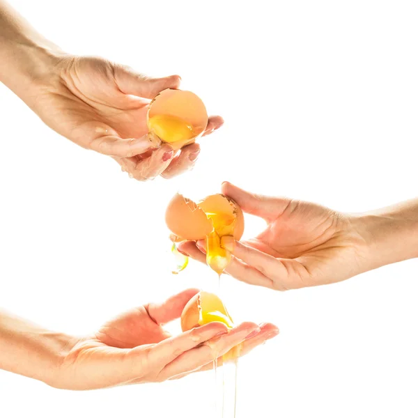 Ręce rozbijania jaj. Żółtka jaj kapanie, spada, biały backg — Zdjęcie stockowe