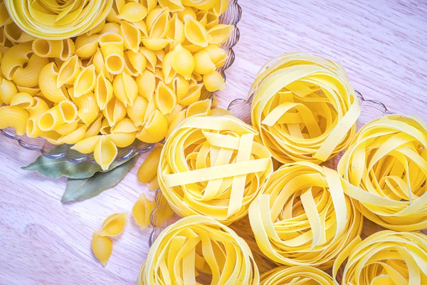 Twee platen met verschillende types van de ruwe pasta op een houten tafel — Stockfoto