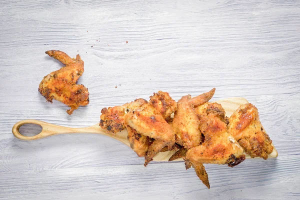Fried chicken wings on cutting board and wooden table with copy space — ストック写真