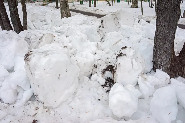 Schneehaufen und Baumstämme in einer Winterstraße — Stockfoto