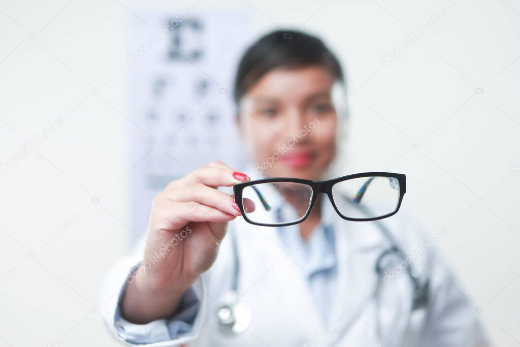 Pair of glasses female doctor with stethoscope and a vision chart at the back
