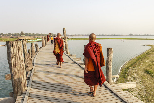 MANDALAY, MYANMAR - FEB 14: Myanmar monks walk on U Bein Bridge where is the oldest and longest teak wooden bridge in the world