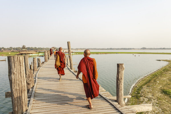 MANDALAY, MYANMAR - FEB 14: Myanmar monks walk on U Bein Bridge where is the oldest and longest teak wooden bridge in the world