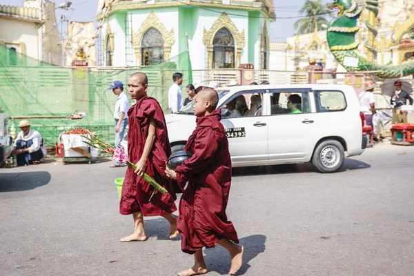 MANDALAY, MYANMAR - FEB 14: Monks walk on U Bein Bridge where is the oldest and longest teak wooden bridge in the world — стоковое фото