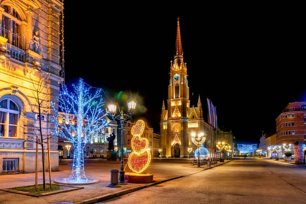 Novi Sad, Sırbistan 05 Ocak 2021: Sırbistan 'ın Novi Sad kentinde noel ışıklarıyla şehir merkezindeki Kutsal Mary kilisesi simgesi.