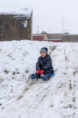 Plastik kızaklı çocuk karda oynuyor.