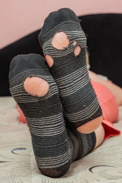 The woman is lying with torn socks. Worn socks.